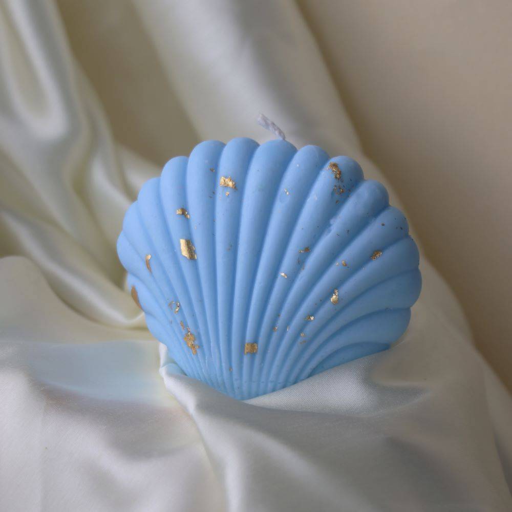 Blue shell-shaped candle with gold accents, perfect for an outdoor nature-inspired display. Adds a coastal charm to home and garden decor.