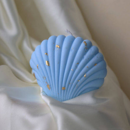 Blue shell-shaped candle with gold accents, perfect for an outdoor nature-inspired display. Adds a coastal charm to home and garden decor.